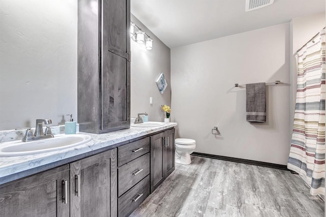 665 Kroll Rd, Pulaski, WI 54162 - full bathroom with double vanity, toilet, wood finished floors, and baseboards