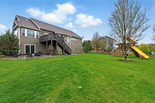 back of house with stairs, a deck, a patio area, a yard, and a fire pit