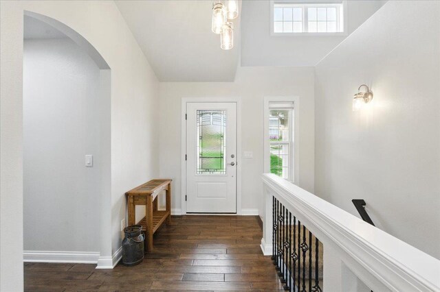 foyer entrance with arched walkways, baseboards, and hardwood / wood-style floors