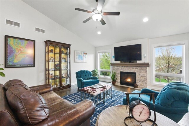 living room featuring visible vents, lofted ceiling, wood finished floors, a fireplace, and ceiling fan