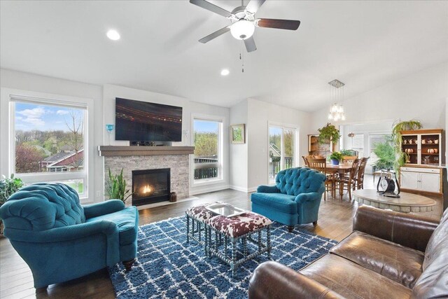 living area with vaulted ceiling, wood finished floors, and ceiling fan with notable chandelier