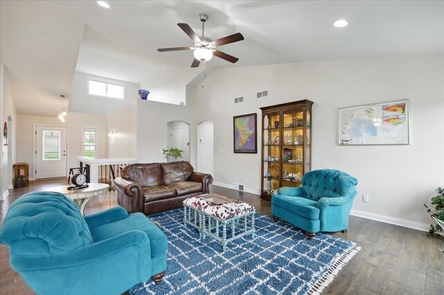 living area with arched walkways, a ceiling fan, baseboards, wood finished floors, and visible vents
