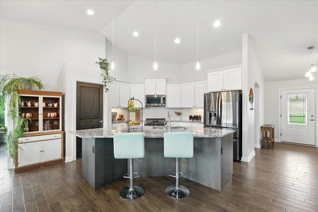 kitchen featuring dark wood finished floors, appliances with stainless steel finishes, white cabinetry, and tasteful backsplash