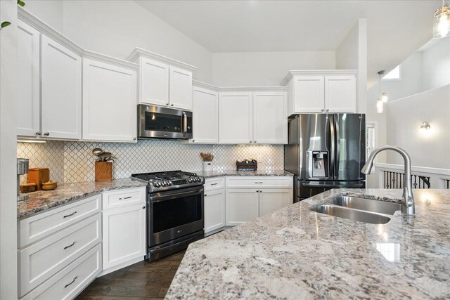 kitchen featuring white cabinets, a sink, dark wood finished floors, stainless steel appliances, and backsplash