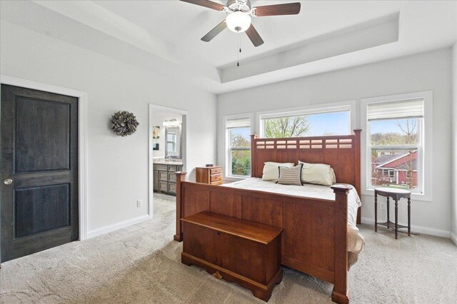 bedroom with baseboards, a tray ceiling, and light carpet