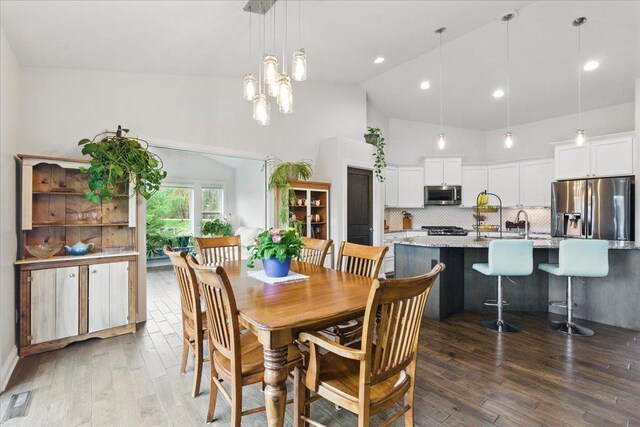 dining space with visible vents, recessed lighting, wood finished floors, and high vaulted ceiling