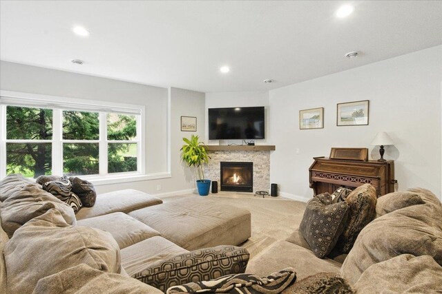 living area with baseboards, carpet, recessed lighting, and a stone fireplace