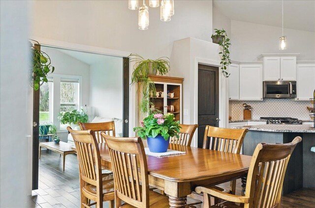 dining area featuring high vaulted ceiling and dark wood finished floors