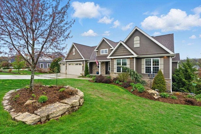 craftsman house featuring a front yard, driveway, an attached garage, and stone siding