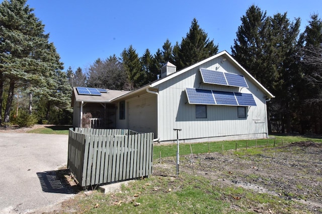 view of front of property with a chimney, an attached garage, and solar panels