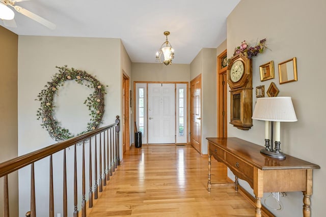 entryway with light wood-style floors and ceiling fan with notable chandelier