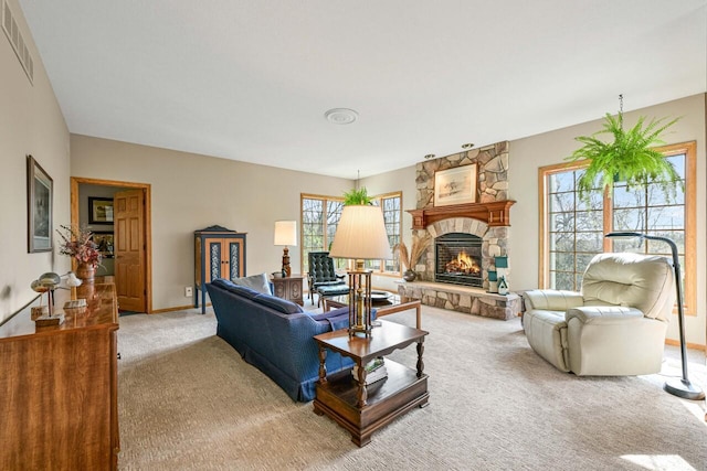 living area featuring light colored carpet, visible vents, a stone fireplace, and baseboards