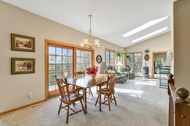 dining space featuring visible vents, baseboards, light carpet, lofted ceiling with skylight, and a notable chandelier