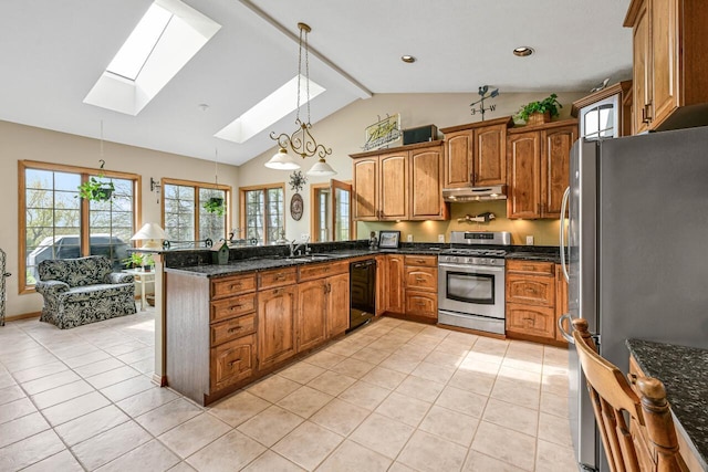 kitchen with brown cabinets, under cabinet range hood, light tile patterned flooring, lofted ceiling with skylight, and appliances with stainless steel finishes