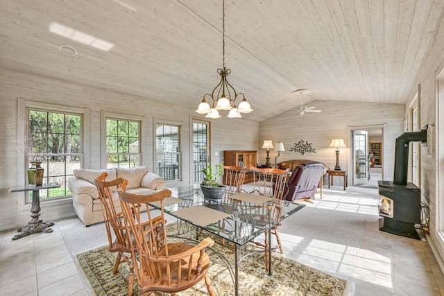dining space featuring a wood stove, light tile patterned floors, vaulted ceiling, wood ceiling, and ceiling fan with notable chandelier
