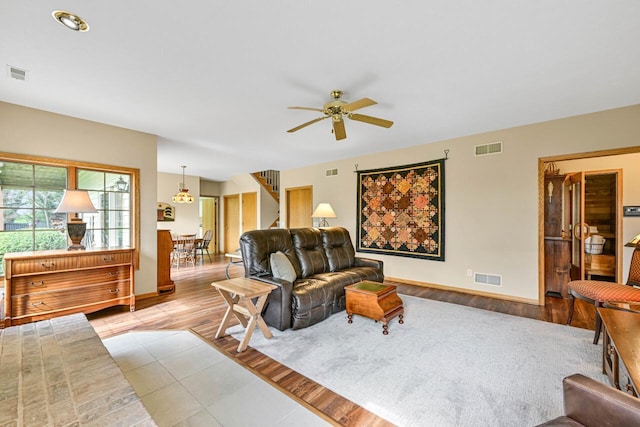 living room featuring visible vents, wood finished floors, a ceiling fan, and stairs