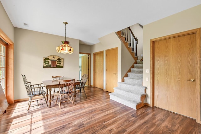 dining room featuring baseboards, stairway, wood finished floors, and visible vents