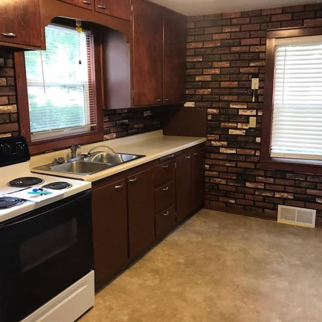 1708 5th St, Menomonie, WI 54751 - kitchen with electric range, visible vents, light countertops, a sink, and brick wall