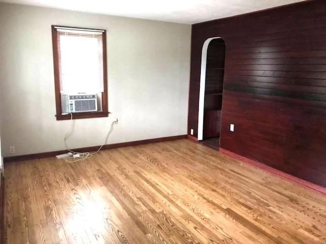 1708 5th St, Menomonie, WI 54751 - unfurnished room featuring cooling unit, arched walkways, wood finished floors, and baseboards