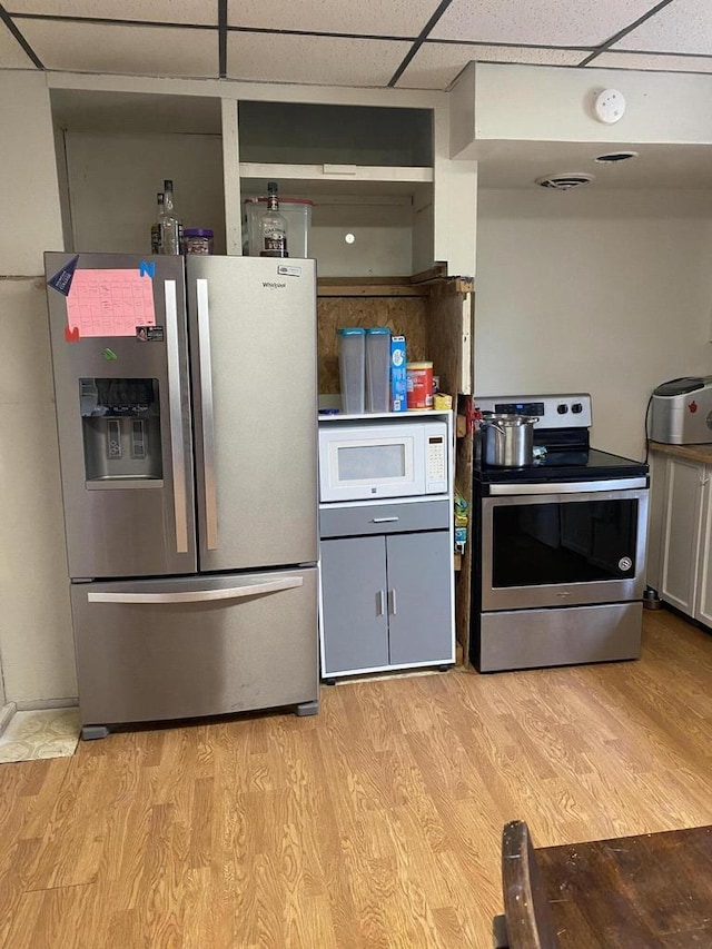 kitchen featuring light wood finished floors, appliances with stainless steel finishes, and a drop ceiling