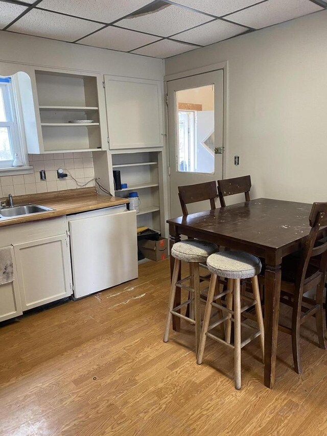 kitchen featuring open shelves, a sink, dishwasher, light wood finished floors, and white cabinets