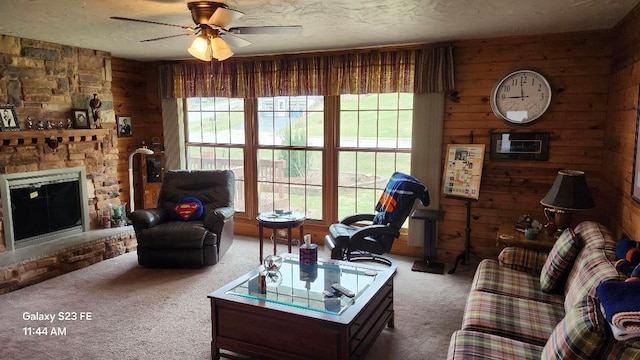 755 Brickley Dr, Fontana, WI 53125 - living room featuring wood walls, a stone fireplace, a ceiling fan, and carpet