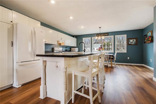 1229 W Beltline Rd, Spring Valley, WI 54767 - kitchen with dark countertops, freestanding refrigerator, a kitchen bar, dark wood-style floors, and stove