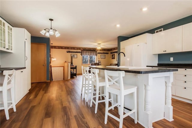 1229 W Beltline Rd, Spring Valley, WI 54767 - kitchen featuring glass insert cabinets, dark wood-type flooring, a kitchen bar, visible vents, and dark countertops