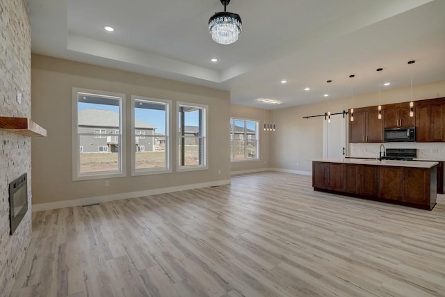 2025 Mulberry St, Sauk City, WI 53583 - kitchen with black microwave, open floor plan, a barn door, a raised ceiling, and stove