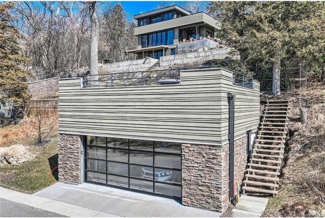 1020 Lake St, Prescott, WI 54021 - exterior space with a garage, stairs, stone siding, and fence