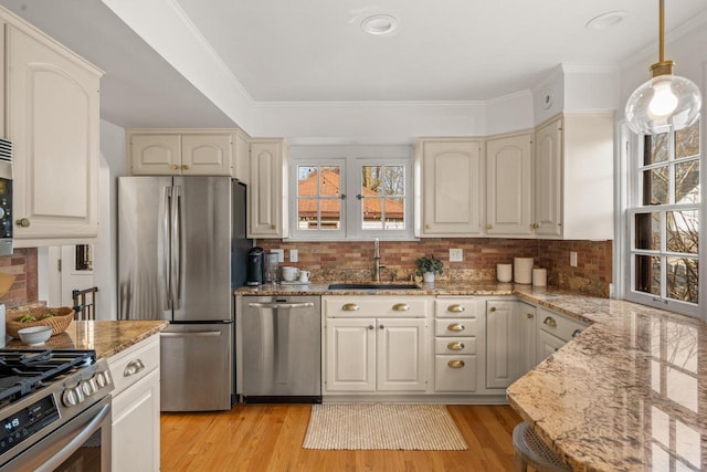 kitchen featuring light stone countertops, appliances with stainless steel finishes, a sink, and light wood-type flooring
