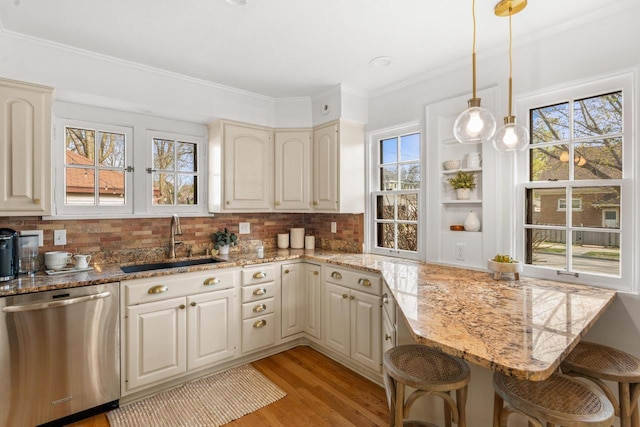 kitchen with a sink, light wood-style floors, a breakfast bar area, and dishwasher