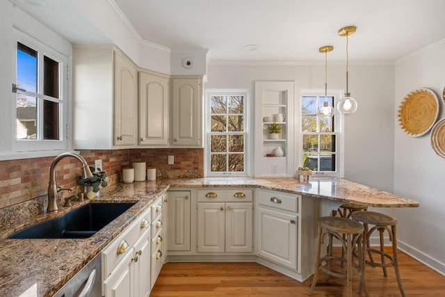 kitchen featuring light wood-style floors, a sink, decorative backsplash, and pendant lighting