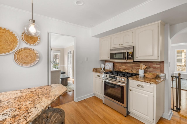 kitchen featuring light stone counters, light wood-style floors, appliances with stainless steel finishes, and tasteful backsplash