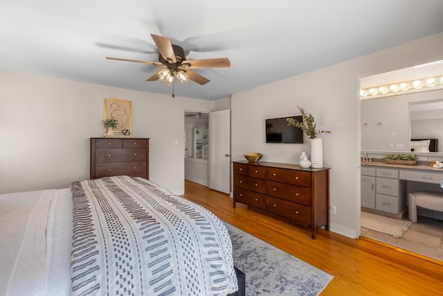 bedroom featuring a sink, ceiling fan, light wood finished floors, and connected bathroom