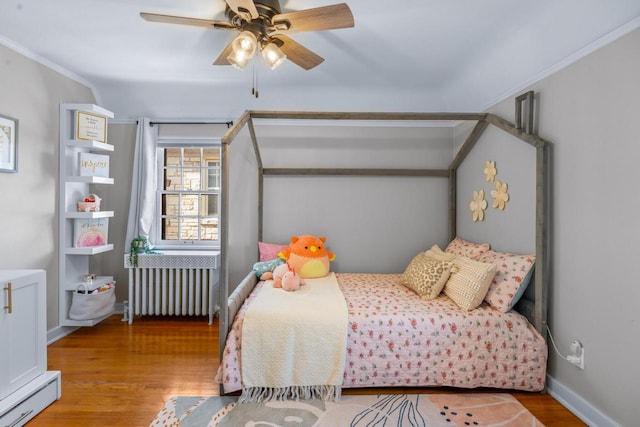 bedroom with radiator heating unit, crown molding, wood finished floors, and ceiling fan