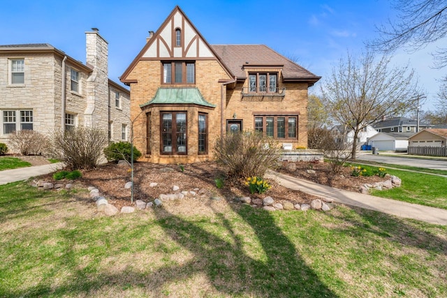 tudor-style house featuring brick siding and a front lawn