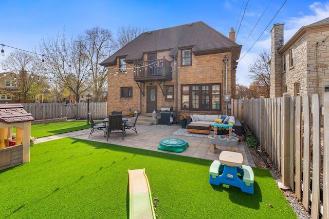 rear view of property with an outdoor living space, a patio area, brick siding, a fenced backyard, and a balcony