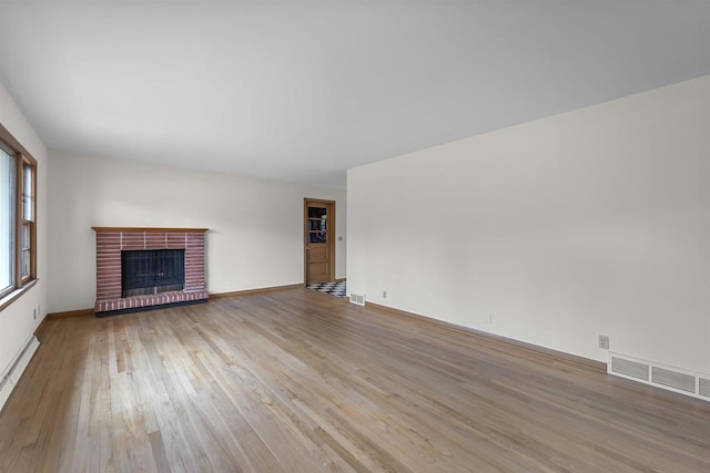 5221 Odana Rd, Madison, WI 53711 - unfurnished living room featuring visible vents, baseboards, a brick fireplace, wood finished floors, and a baseboard heating unit