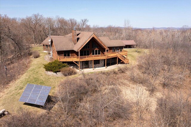 N8718 County Road Vv, Mindoro, WI 54644 - rear view of property with ground mounted solar panels, a chimney, and stone siding