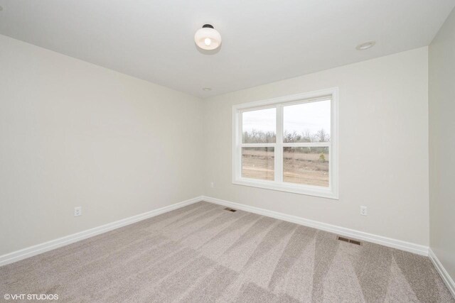 carpeted empty room featuring baseboards and visible vents