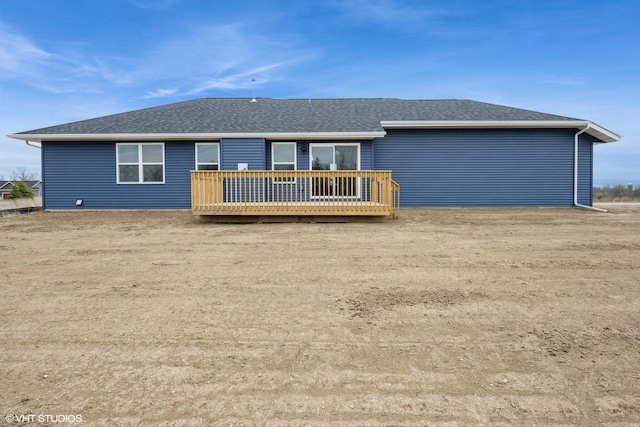 back of property with a shingled roof and a deck