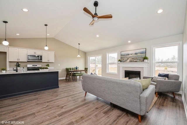 living room featuring recessed lighting, a fireplace, a ceiling fan, lofted ceiling, and wood finished floors