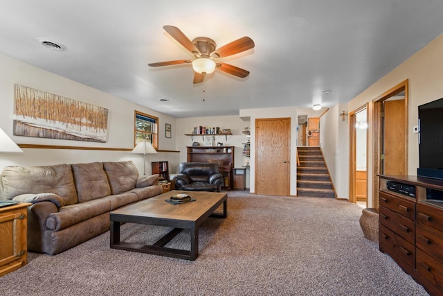 living area featuring visible vents, ceiling fan, stairway, and carpet floors