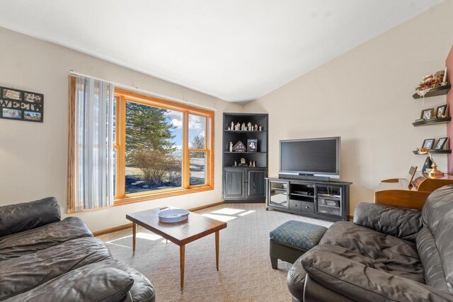 carpeted living room with baseboards and lofted ceiling