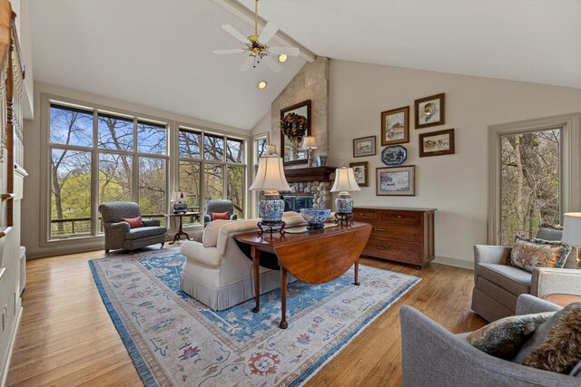 home office featuring a fireplace, beamed ceiling, ceiling fan, high vaulted ceiling, and light wood-style flooring