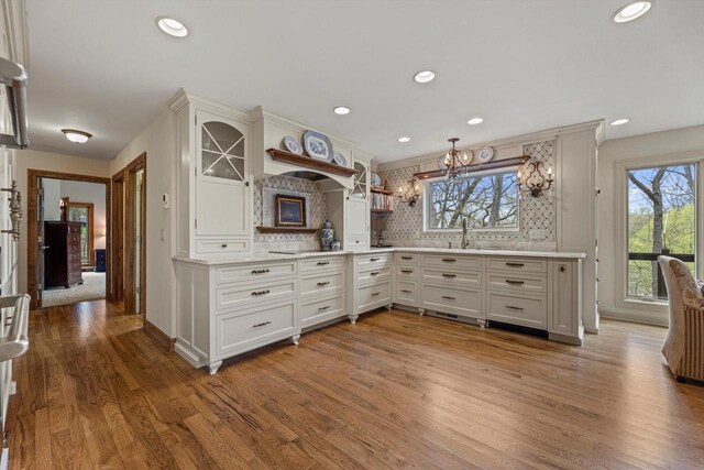 kitchen featuring plenty of natural light, light wood finished floors, and backsplash
