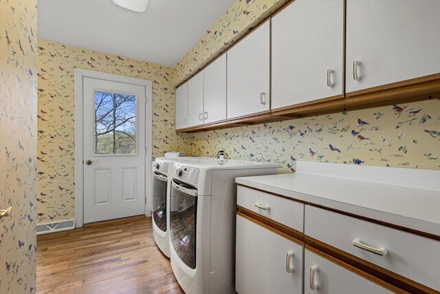 laundry area with visible vents, cabinet space, wallpapered walls, light wood-style flooring, and washer and dryer