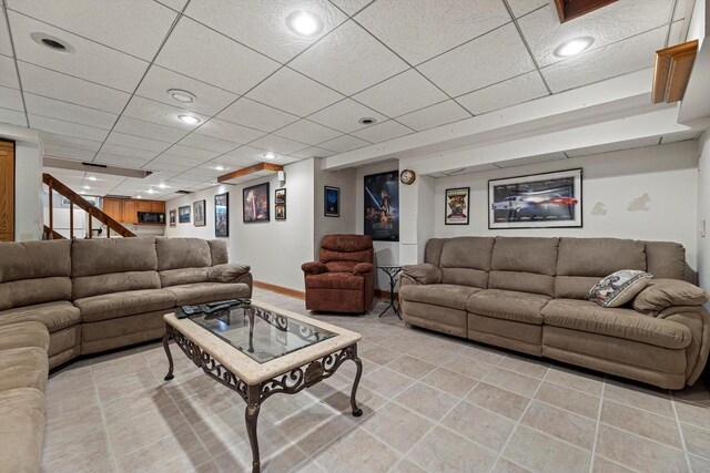 living room with baseboards, stairs, light tile patterned floors, and a drop ceiling
