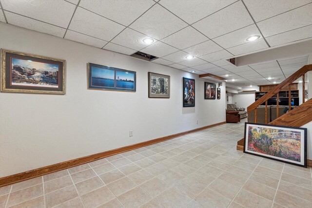 finished basement with baseboards, recessed lighting, a drop ceiling, and stairway